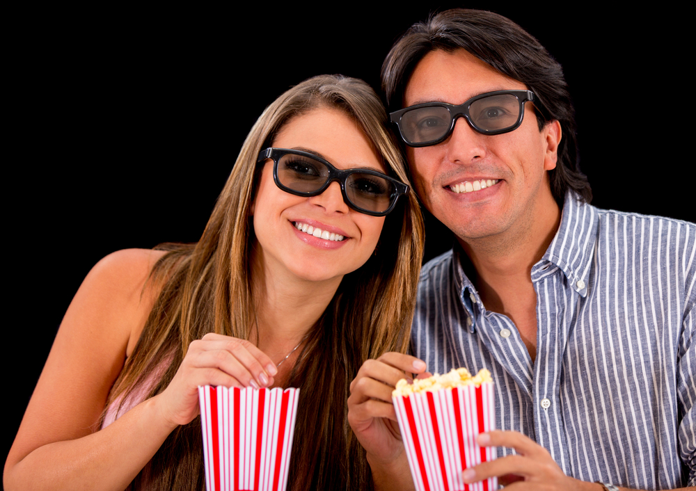 Happy couple watching a 3D movie and wearing glasses